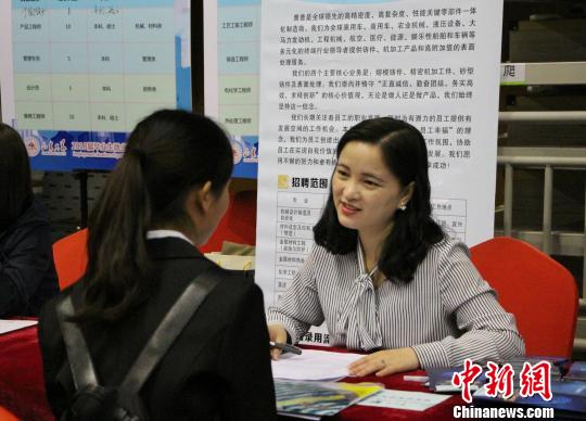 图为企事业单位负责招聘的工作人员与前来找工作的学生进行交流。　赵晓 摄